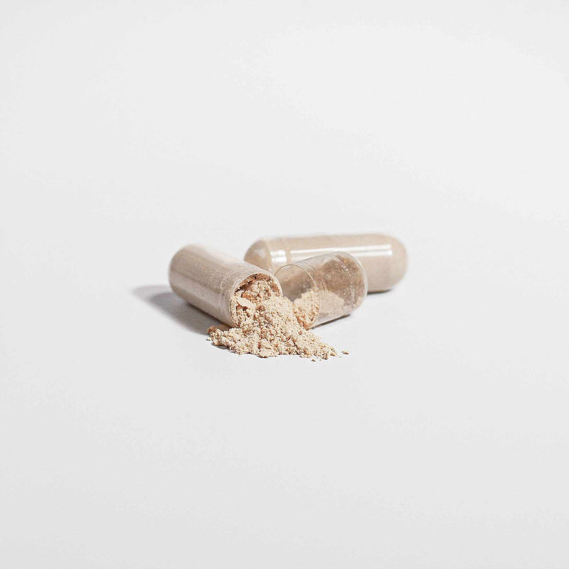 Organic Reishi Mushroom Capsules with powder spilling out on a white background.